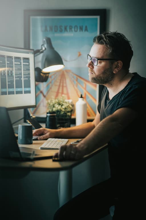 Man wearing glasses, focused in front of a computer monitor