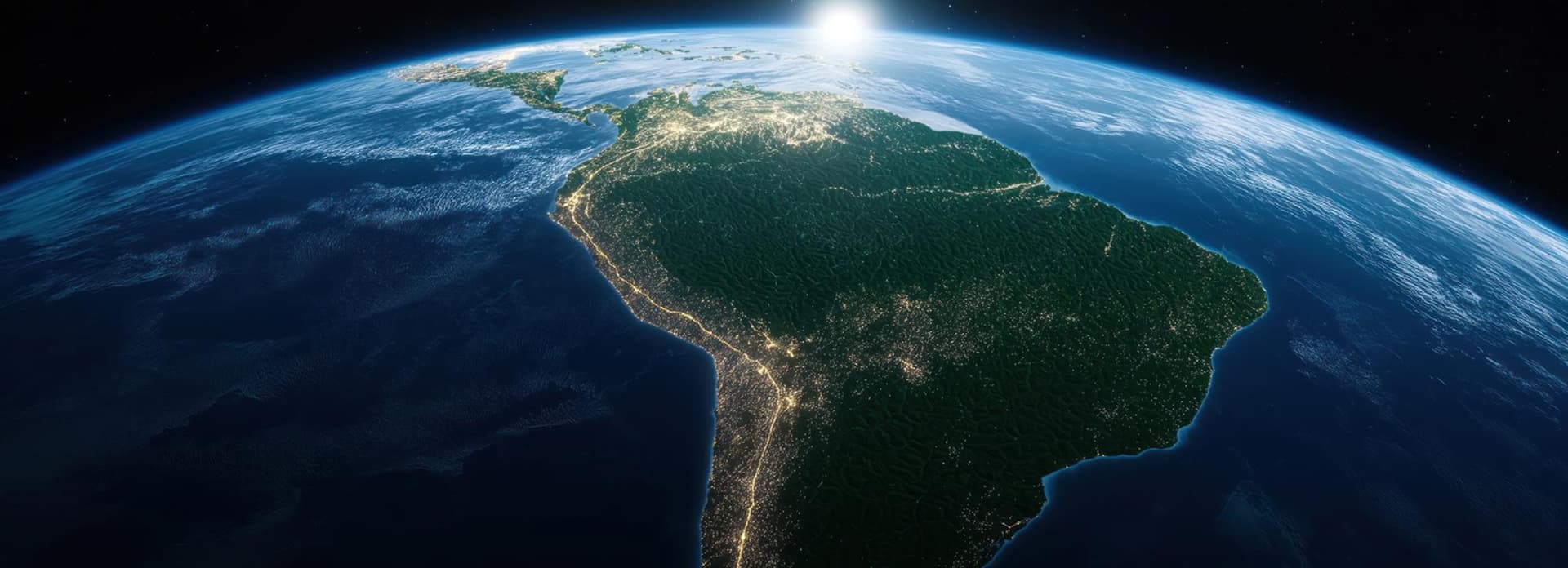 View of Earth from space highlighting South America at night, illuminated city lights visible, with the sun rising on the horizon.